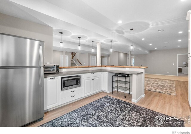 1976 Cayman Dr, Windsor, CO 80550 - kitchen featuring appliances with stainless steel finishes, light wood-style flooring, open floor plan, white cabinets, and recessed lighting