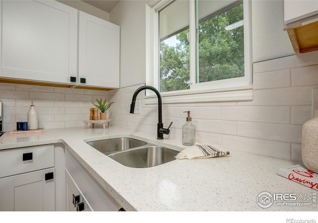 1206 Dawn Ave, Gilcrest, CO 80623 - kitchen with white cabinetry, decorative backsplash, and light stone countertops