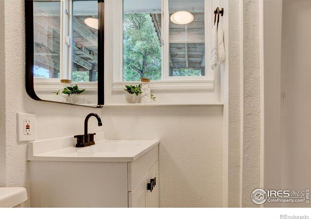 1206 Dawn Ave, Gilcrest, CO 80623 - bathroom with vanity, a textured wall, and healthy amount of natural light