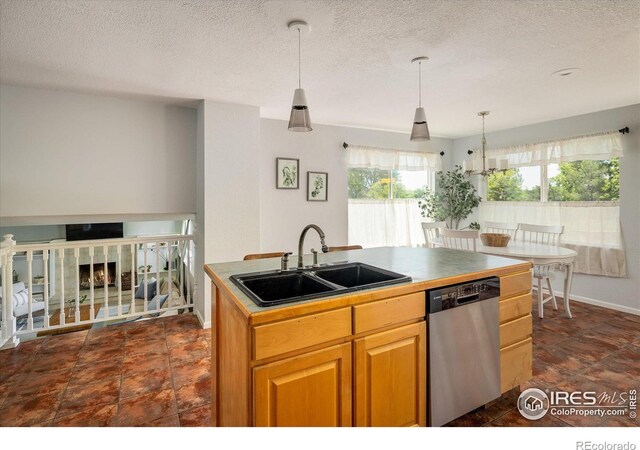 322 W Harper St, Louisville, CO 80027 - kitchen featuring dishwasher, a textured ceiling, an island with sink, decorative light fixtures, and a lit fireplace