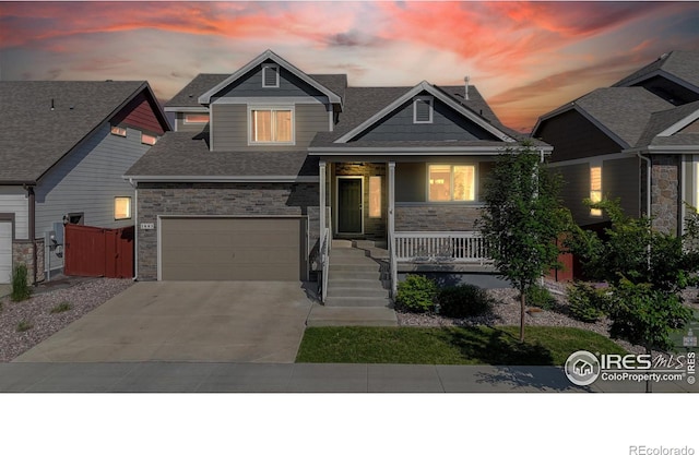 1661 Rise Dr, Windsor, CO 80550 - craftsman-style home featuring covered porch, concrete driveway, a shingled roof, and stone siding