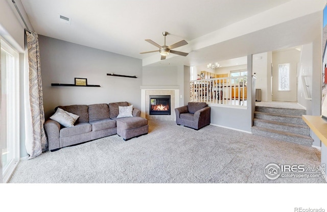 1661 Rise Dr, Windsor, CO 80550 - living room featuring carpet, ceiling fan, a tile fireplace, and stairway