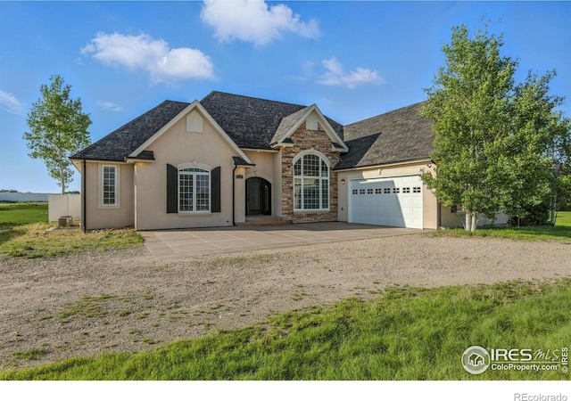 64 Bachar Dr, Fort Morgan, CO 80701 - view of front facade with stone siding, driveway, an attached garage, and stucco siding