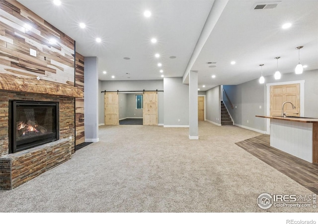 64 Bachar Dr, Fort Morgan, CO 80701 - unfurnished living room with a barn door, stairway, light carpet, recessed lighting, and a large fireplace