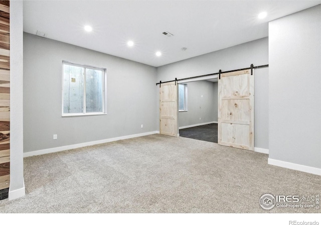 64 Bachar Dr, Fort Morgan, CO 80701 - unfurnished bedroom featuring a barn door, carpet flooring, and recessed lighting