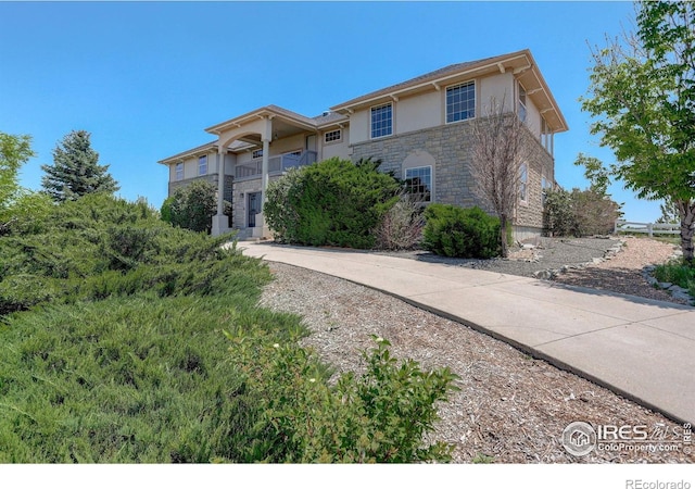 14448 Hanover St, Brighton, CO 80602 - view of front of property with stone siding, stucco siding, and a balcony