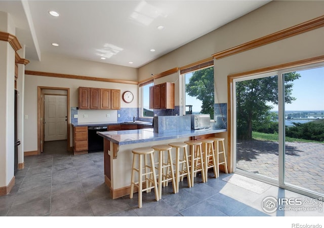 14448 Hanover St, Brighton, CO 80602 - kitchen with black dishwasher, a peninsula, backsplash, a kitchen bar, and recessed lighting