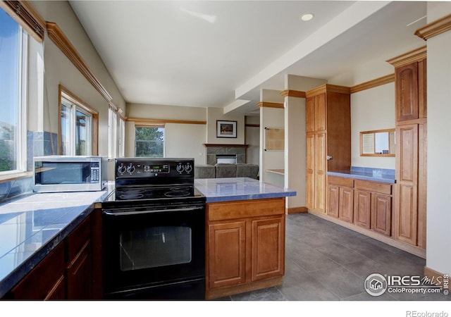 14448 Hanover St, Brighton, CO 80602 - kitchen with black range with electric stovetop, stainless steel microwave, a fireplace, backsplash, and dark tile patterned flooring
