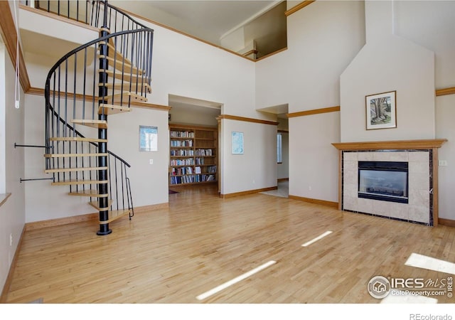 14448 Hanover St, Brighton, CO 80602 - unfurnished living room with wood finished floors, a towering ceiling, stairway, and a tile fireplace