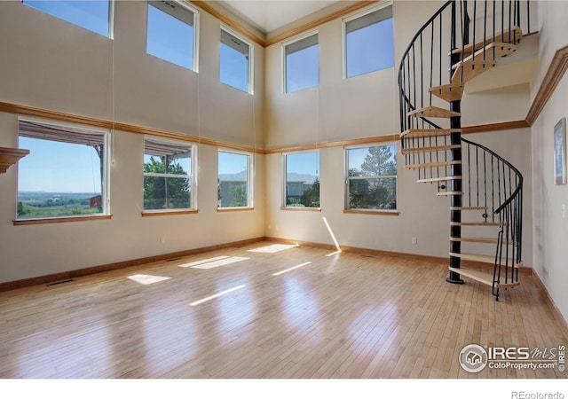 14448 Hanover St, Brighton, CO 80602 - unfurnished living room featuring plenty of natural light, hardwood / wood-style flooring, a towering ceiling, and stairway