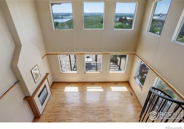 14448 Hanover St, Brighton, CO 80602 - unfurnished living room with a towering ceiling, healthy amount of natural light, wood finished floors, and a water view