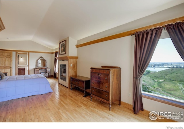 14448 Hanover St, Brighton, CO 80602 - bedroom featuring a tile fireplace, light wood-style floors, and vaulted ceiling