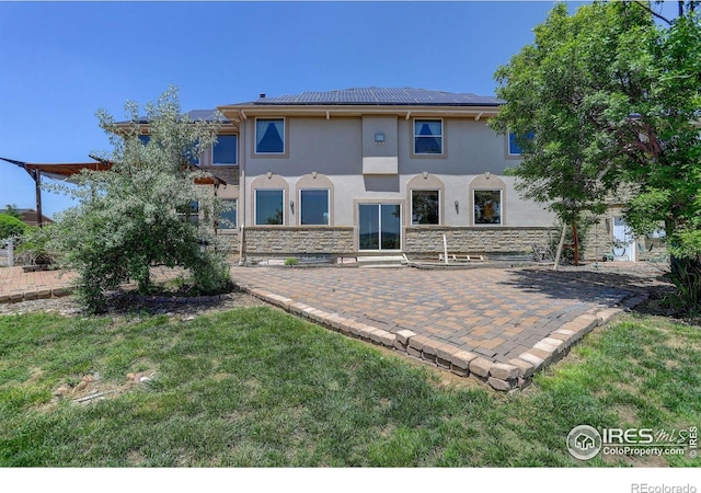 14448 Hanover St, Brighton, CO 80602 - back of house featuring stone siding, stucco siding, a patio area, and a yard