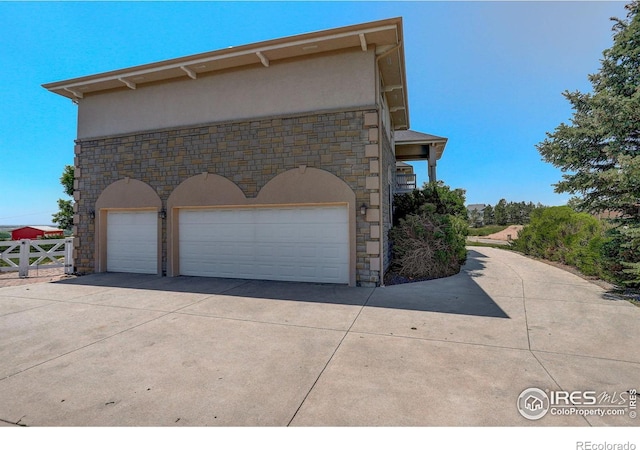 14448 Hanover St, Brighton, CO 80602 - view of side of property featuring stone siding, stucco siding, a garage, and concrete driveway