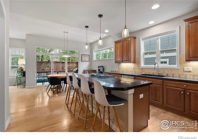 1043 Terrace Cir S, Boulder, CO 80304 - kitchen featuring light wood-style flooring, brown cabinets, a kitchen breakfast bar, backsplash, and a center island