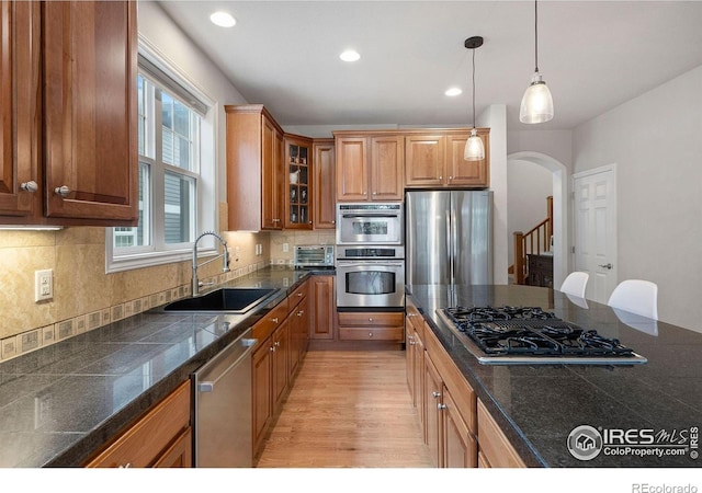 1043 Terrace Cir S, Boulder, CO 80304 - kitchen featuring stainless steel appliances, tile countertops, arched walkways, glass insert cabinets, and brown cabinets