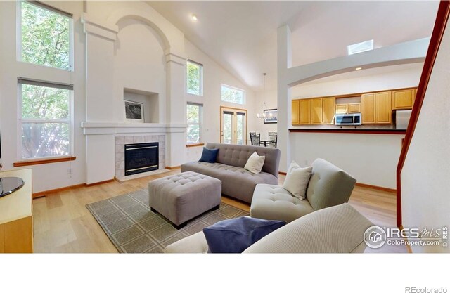 13673 Cook St, Thornton, CO 80602 - living room with a towering ceiling, light wood-style flooring, a tile fireplace, and recessed lighting