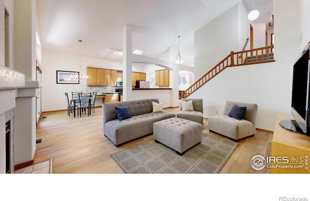 13673 Cook St, Thornton, CO 80602 - living area with light wood-type flooring, high vaulted ceiling, stairs, a tile fireplace, and arched walkways