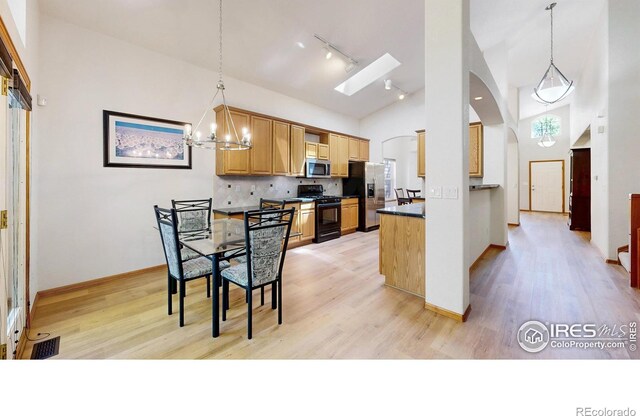 13673 Cook St, Thornton, CO 80602 - kitchen with appliances with stainless steel finishes, arched walkways, track lighting, dark countertops, and light wood-style flooring