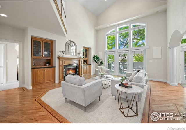 5753 Secrest Ct, Golden, CO 80403 - living area with a glass covered fireplace, high vaulted ceiling, light wood-style flooring, arched walkways, and decorative columns