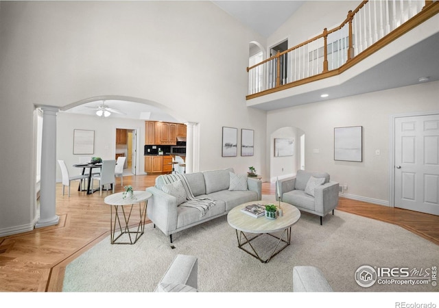 5753 Secrest Ct, Golden, CO 80403 - living room featuring arched walkways, decorative columns, high vaulted ceiling, light wood finished floors, and a ceiling fan