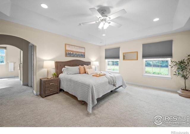 5753 Secrest Ct, Golden, CO 80403 - bedroom featuring light carpet, a raised ceiling, arched walkways, multiple windows, and recessed lighting