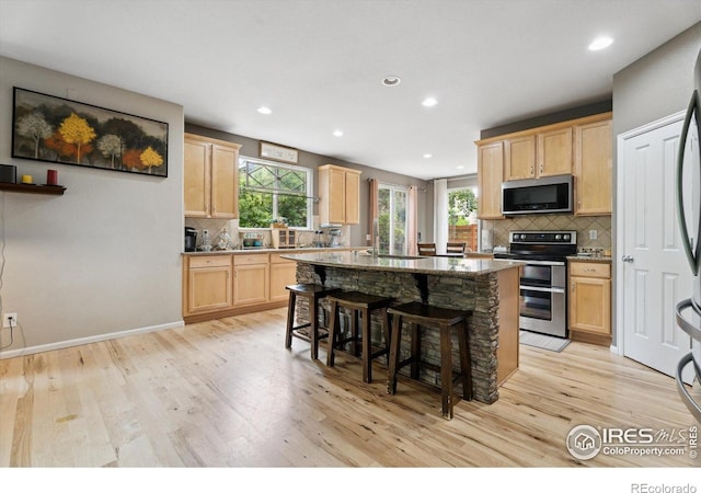 13266 Teller Lake Way, Broomfield, CO 80020 - kitchen featuring appliances with stainless steel finishes, light brown cabinetry, tasteful backsplash, a kitchen island, and recessed lighting