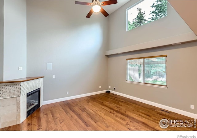 1616 Cedarwood Dr, Longmont, CO 80504 - unfurnished living room featuring plenty of natural light, wood finished floors, a ceiling fan, high vaulted ceiling, and a tile fireplace