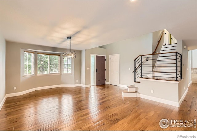 1616 Cedarwood Dr, Longmont, CO 80504 - unfurnished living room featuring stairs, a chandelier, and wood-type flooring