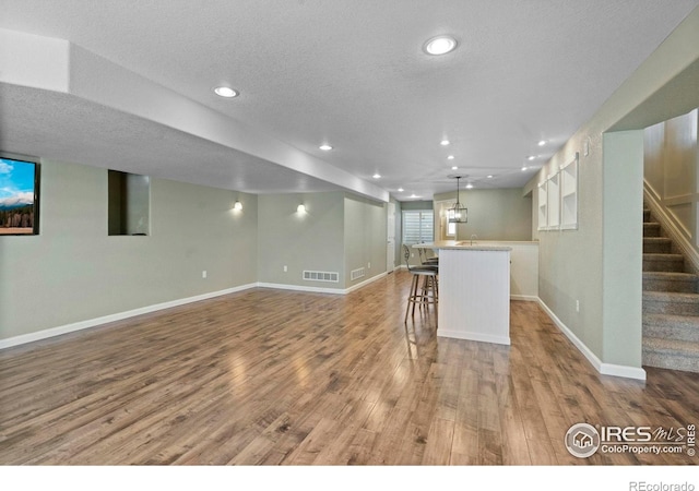 2833 Annelise Way, Fort Collins, CO 80525 - basement featuring wood finished floors, a textured ceiling, stairs, wet bar, and recessed lighting