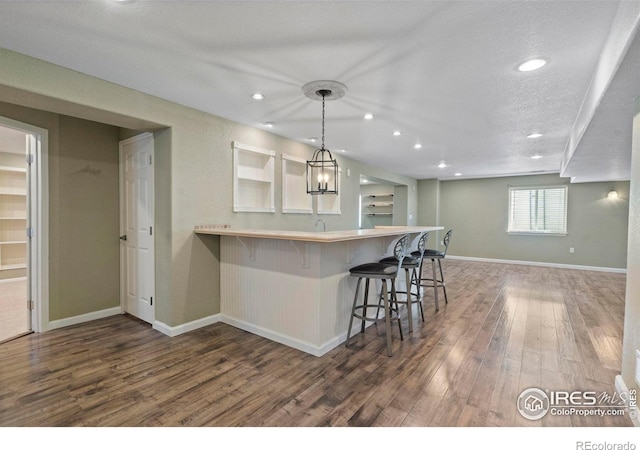 2833 Annelise Way, Fort Collins, CO 80525 - kitchen with wood finished floors, a kitchen bar, recessed lighting, a peninsula, and hanging light fixtures