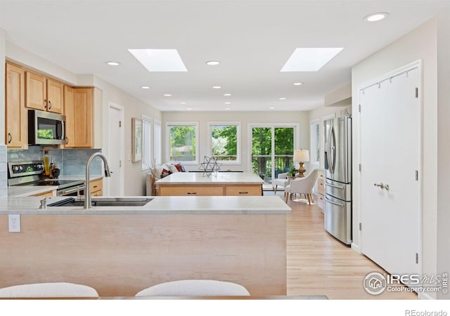 2016 Strathmore St, Louisville, CO 80027 - kitchen featuring a skylight, appliances with stainless steel finishes, light wood finished floors, light brown cabinetry, and recessed lighting