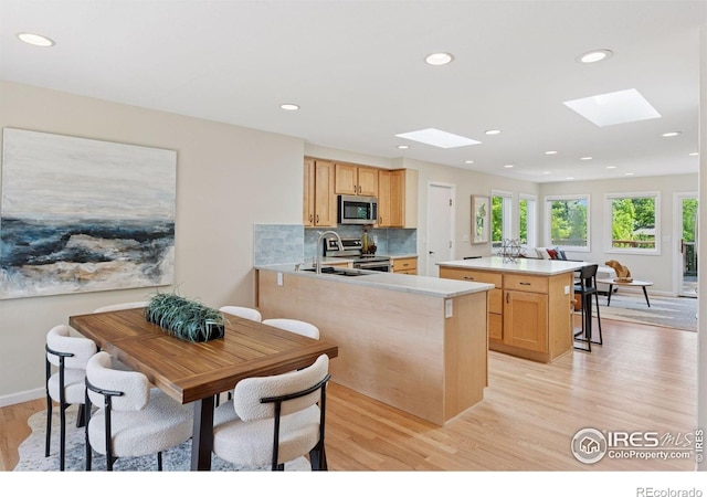 2016 Strathmore St, Louisville, CO 80027 - kitchen featuring stainless steel appliances, a skylight, light wood-style floors, light countertops, and light brown cabinetry