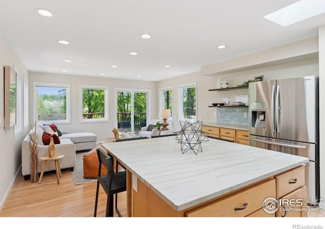 2016 Strathmore St, Louisville, CO 80027 - kitchen featuring stainless steel fridge with ice dispenser, light brown cabinets, open floor plan, light wood-style flooring, and a skylight