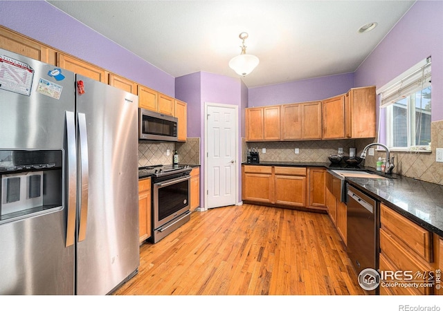 9673 Roadrunner Ave, Firestone, CO 80504 - kitchen featuring stainless steel appliances, dark countertops, light wood finished floors, tasteful backsplash, and brown cabinetry