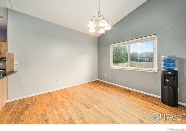 9673 Roadrunner Ave, Firestone, CO 80504 - unfurnished dining area with a chandelier, wood finished floors, and vaulted ceiling
