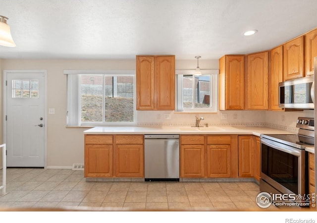 7162 Quay St, Arvada, CO 80003 - kitchen with stainless steel appliances, light countertops, hanging light fixtures, light tile patterned floors, and recessed lighting