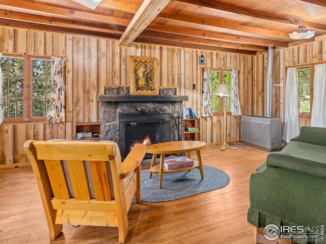 84 County Road 113 N, Allenspark, CO 80510 - living room with a wooden ceiling with exposed beams, healthy amount of natural light, a lit fireplace, wooden walls, and wood-type flooring