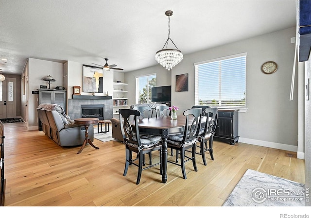 1101 Hillside Ln, Louisville, CO 80027 - dining room with a ceiling fan, a chandelier, light wood-style floors, and a fireplace