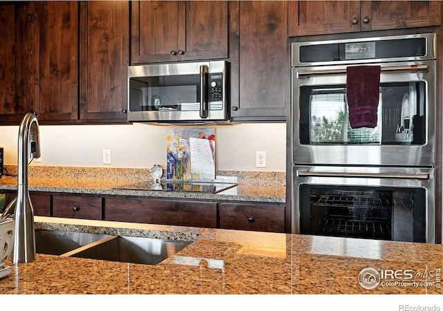 1101 Hillside Ln, Louisville, CO 80027 - kitchen with appliances with stainless steel finishes, dark brown cabinetry, and light stone countertops
