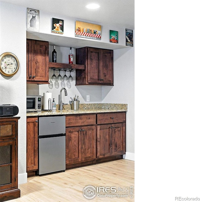 1101 Hillside Ln, Louisville, CO 80027 - kitchen featuring stainless steel appliances, open shelves, light wood-type flooring, and light stone countertops
