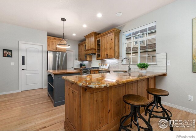2006 Mackenzie Ct, Fort Collins, CO 80528 - kitchen with appliances with stainless steel finishes, a center island, light wood-type flooring, light stone countertops, and brown cabinetry