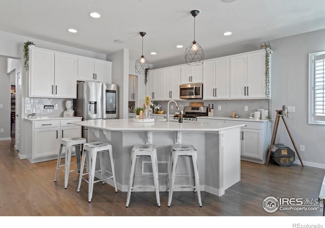 2332 Tabor St, Berthoud, CO 80513 - kitchen with stainless steel appliances, wood finished floors, white cabinets, a breakfast bar area, and recessed lighting