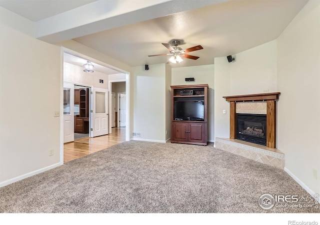 6544 Saddleback Ave, Longmont, CO 80504 - unfurnished living room with carpet flooring, ceiling fan, and a tile fireplace