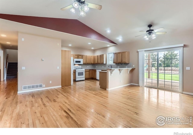 6544 Saddleback Ave, Longmont, CO 80504 - kitchen featuring white appliances, a ceiling fan, a peninsula, a kitchen breakfast bar, and vaulted ceiling