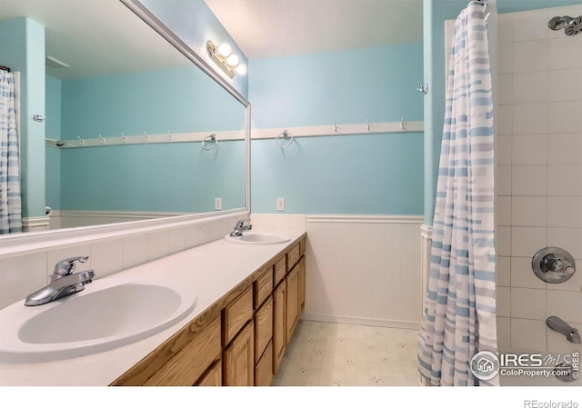 6544 Saddleback Ave, Longmont, CO 80504 - bathroom with wainscoting, double vanity, and tile patterned floors