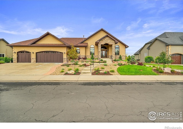 8406 Spinnaker Bay Dr, Windsor, CO 80528 - view of front facade featuring stucco siding, stone siding, an attached garage, and driveway