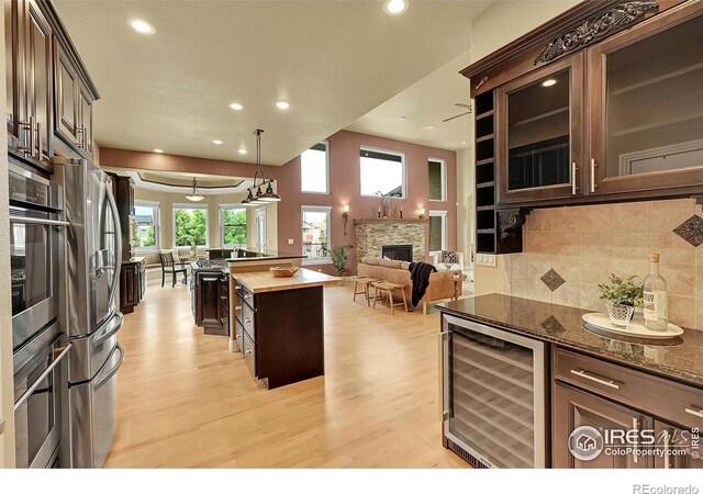 8406 Spinnaker Bay Dr, Windsor, CO 80528 - kitchen featuring wine cooler, light wood-style floors, stainless steel appliances, open floor plan, and backsplash