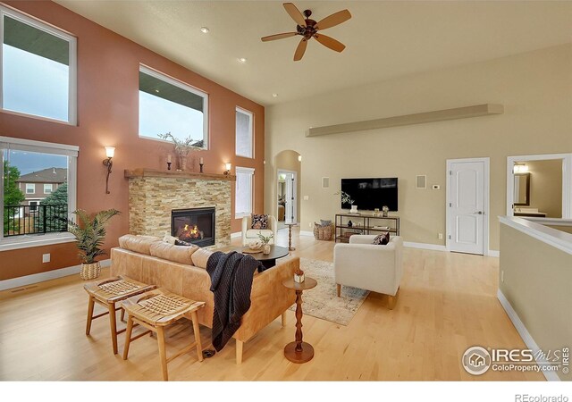 8406 Spinnaker Bay Dr, Windsor, CO 80528 - living room with a towering ceiling, light wood finished floors, ceiling fan, arched walkways, and a fireplace