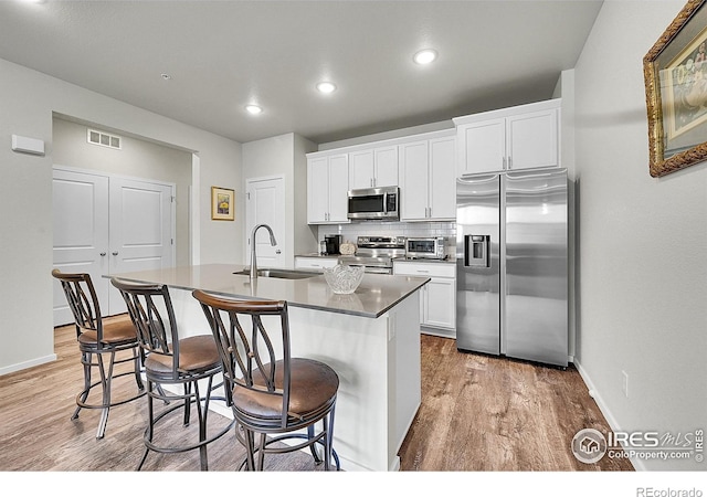 551 Vicot Way Unit D, Fort Collins, CO 80524 - kitchen featuring stainless steel appliances, light wood finished floors, an island with sink, a kitchen bar, and white cabinetry